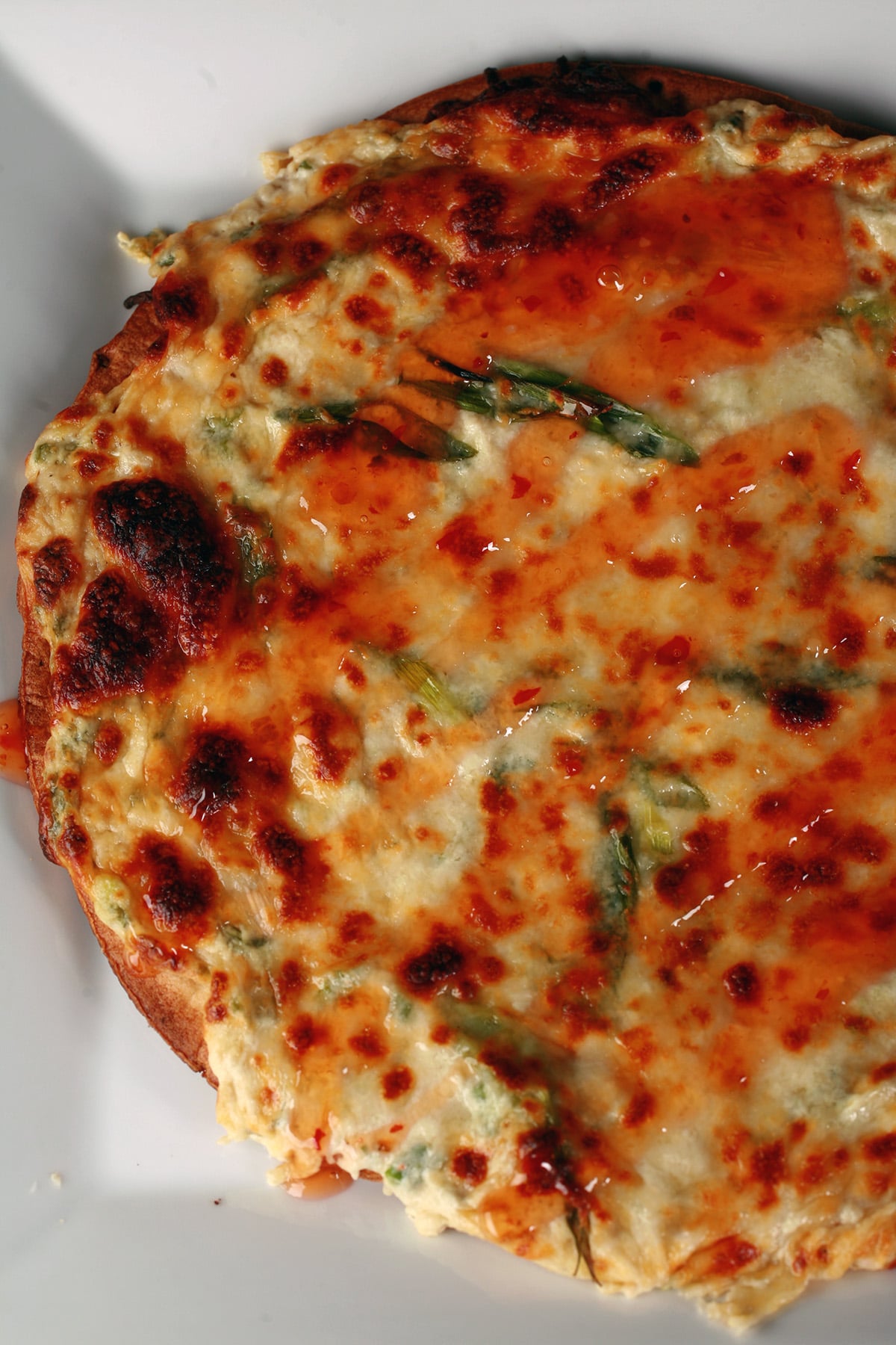 A close up view of a whole crab rangoon pizza, thin crust.