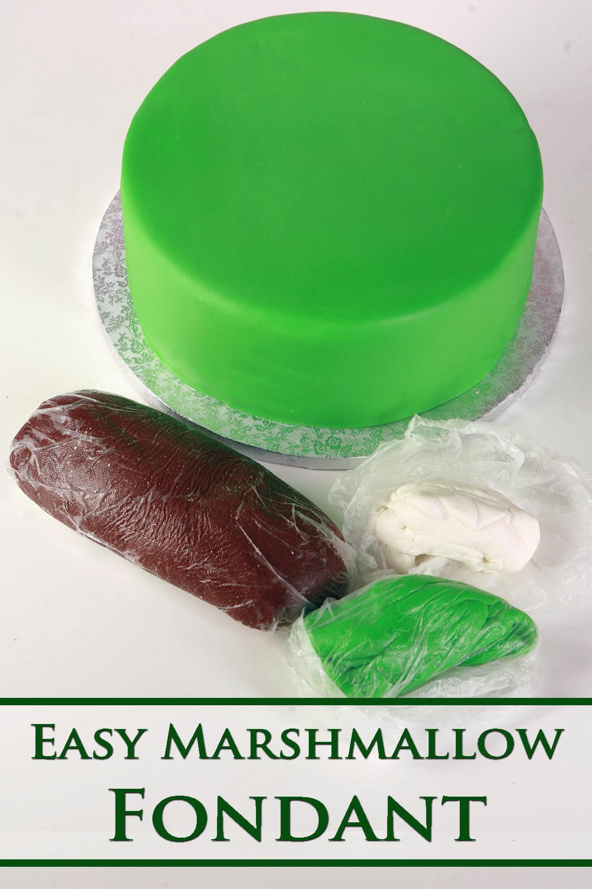 3 logs of marshmallow fondant - one brown, one greem, and one white - are in the foreground. A large round cake covered with smooth green fondant is in the background.