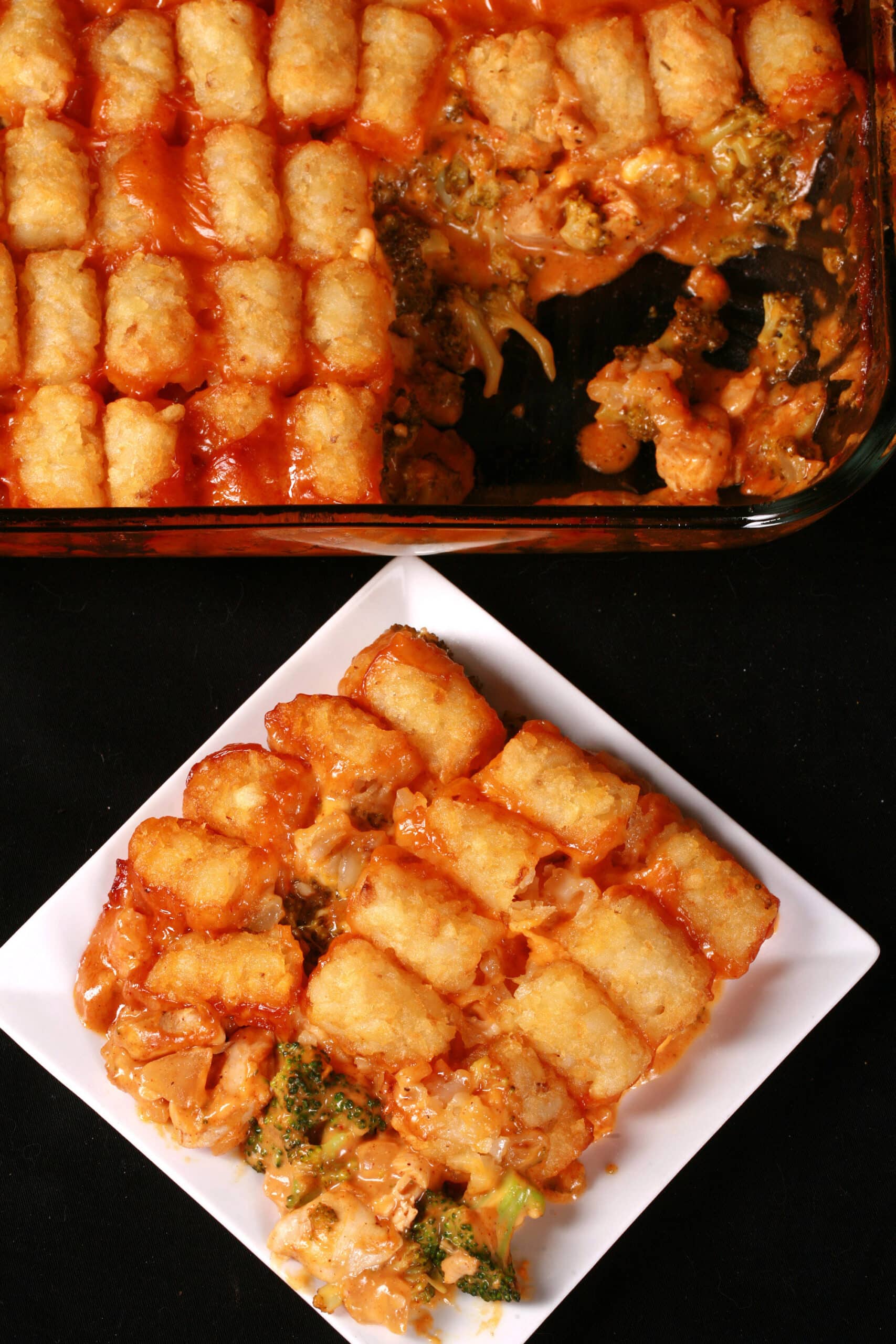A pan and plate of chicken and broccoli casserole with tater tots on top.