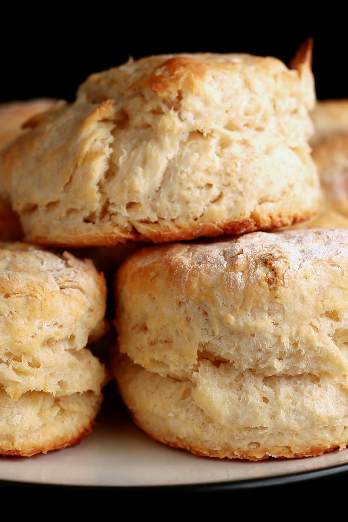 A close up view of several golden baking powder buttermilk biscuits on a plate.