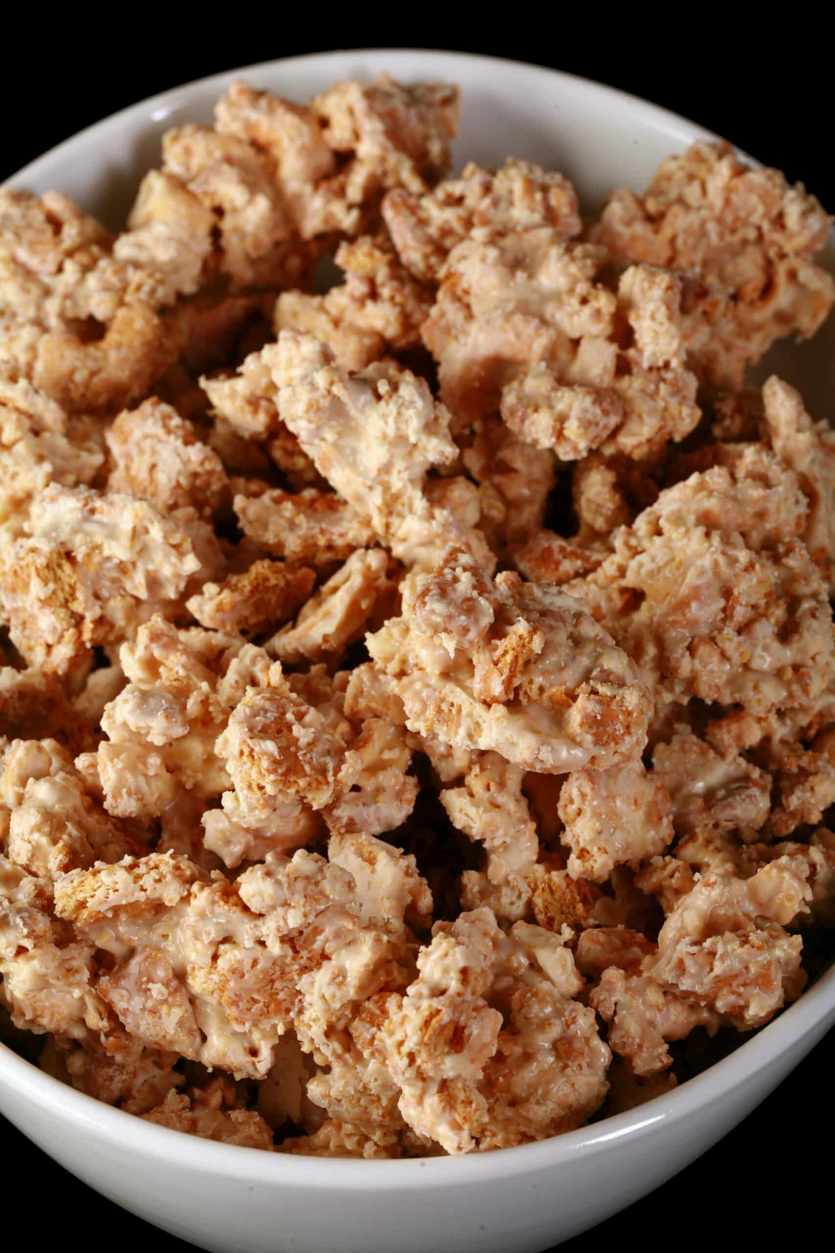 A bowl of homemade clodhoppers candy: clusters of cashew pieces, graham crackers, and white chocolate.