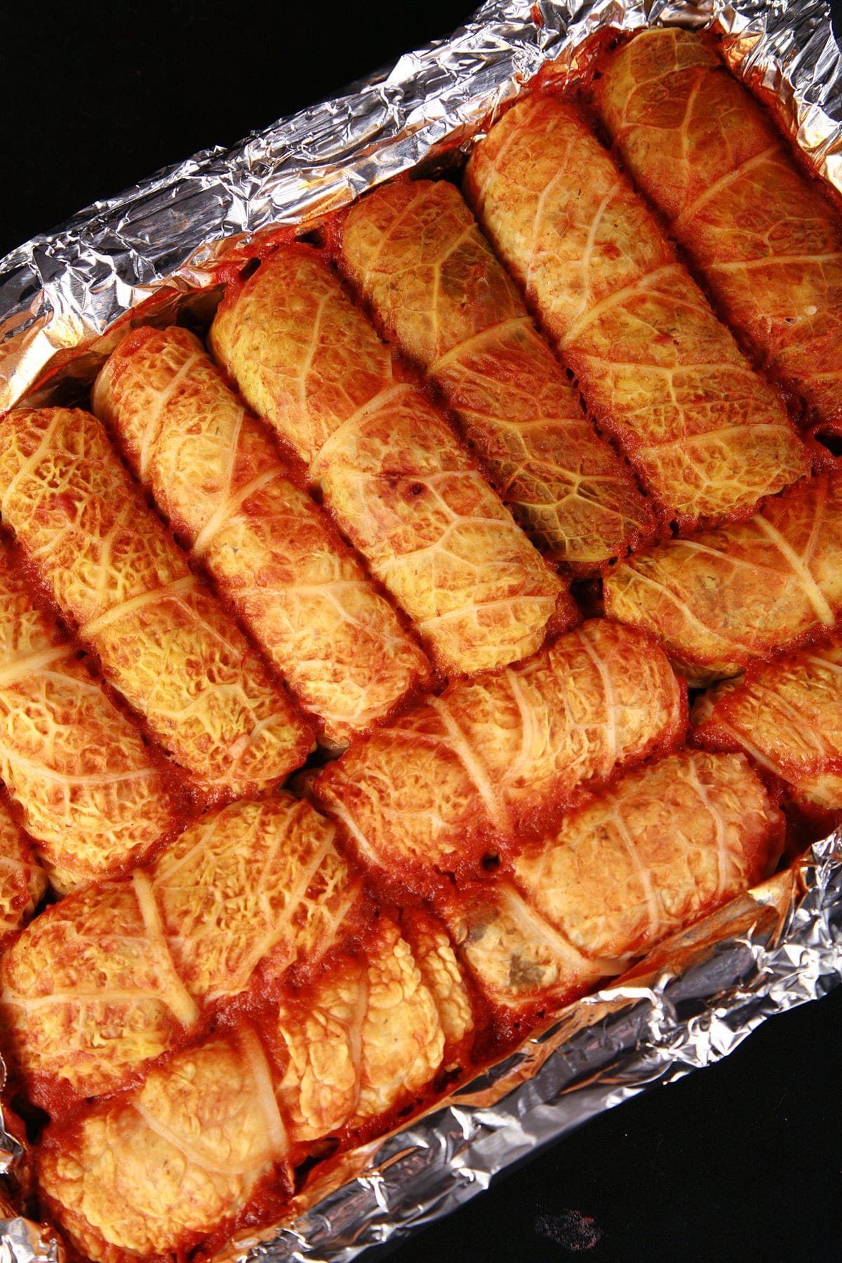 A close up view of a pan of V* covered cabbage rolls.