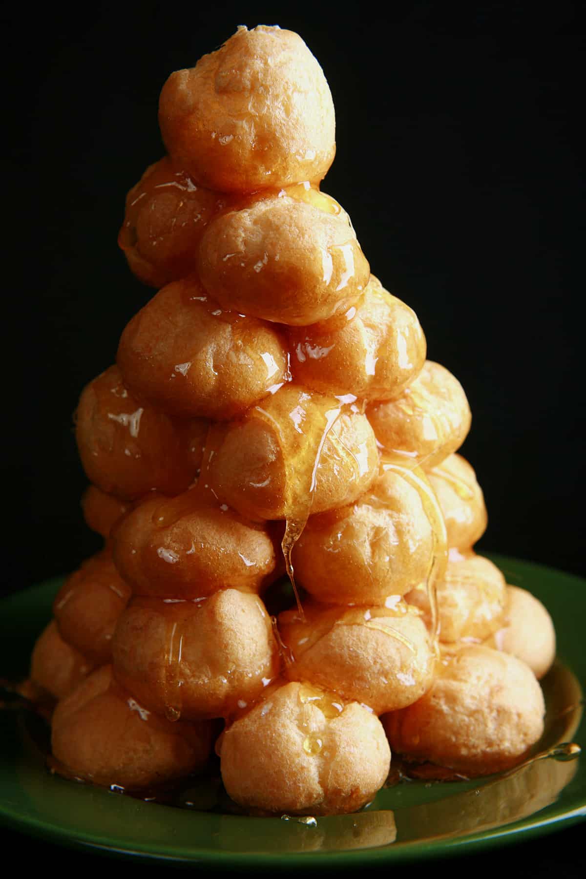 A croquembouche pastry tower with caramel shown dripping between layers.