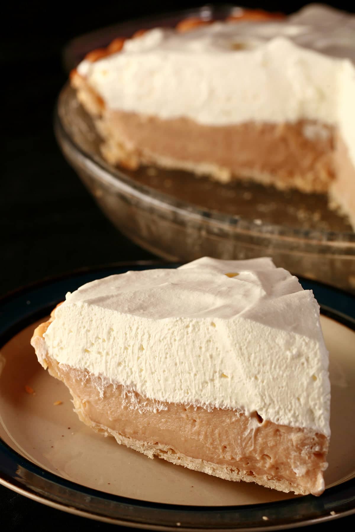 A slice of Earl Grey Custard Pie - A greige custard pie, topped with whipped cream.