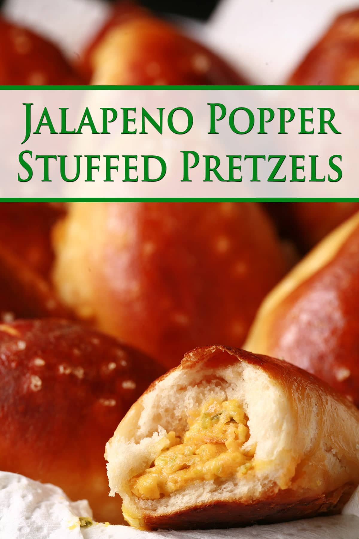 A napkin lined plastic food basket is full of golden brown jalapeno popper stuffed pretzels. In the foreground, one of the buns has a bite taken out, revealing a jalapeno and cheese filling.