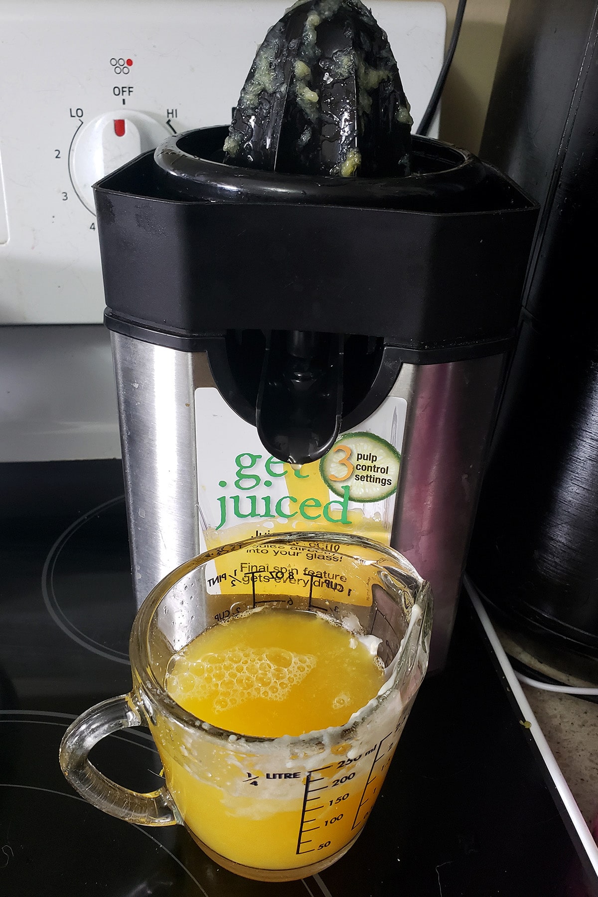 An electric juicer being used for orange juice.