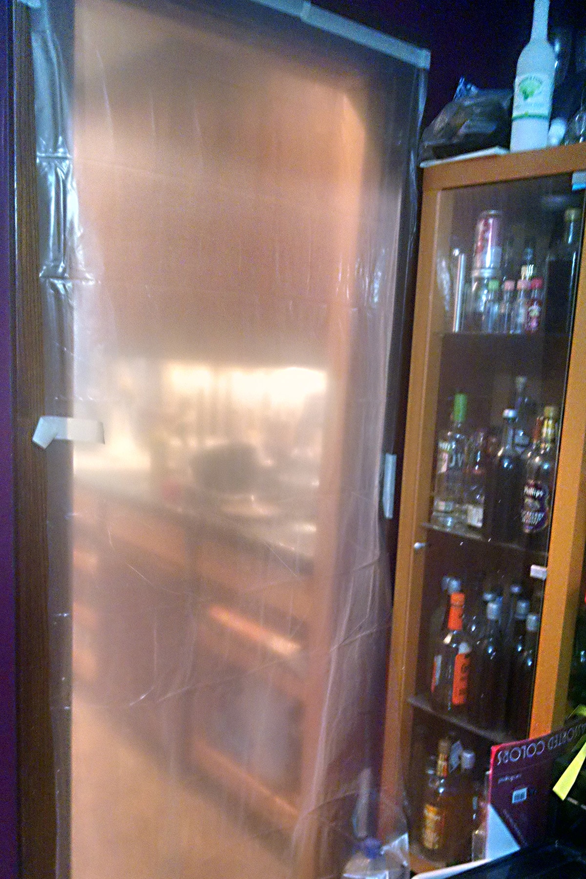 The view of a kitchen door, covered with a thick, translucent plastic.