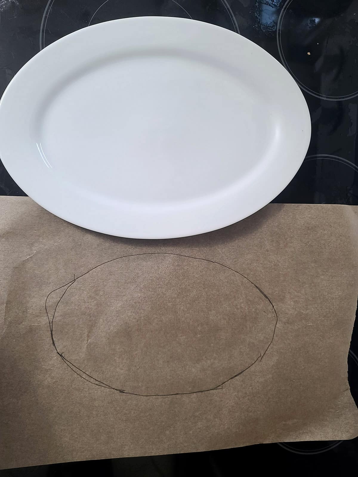 A 2 part image showing an oval platter and a parchment paper with an oval drawn on it.