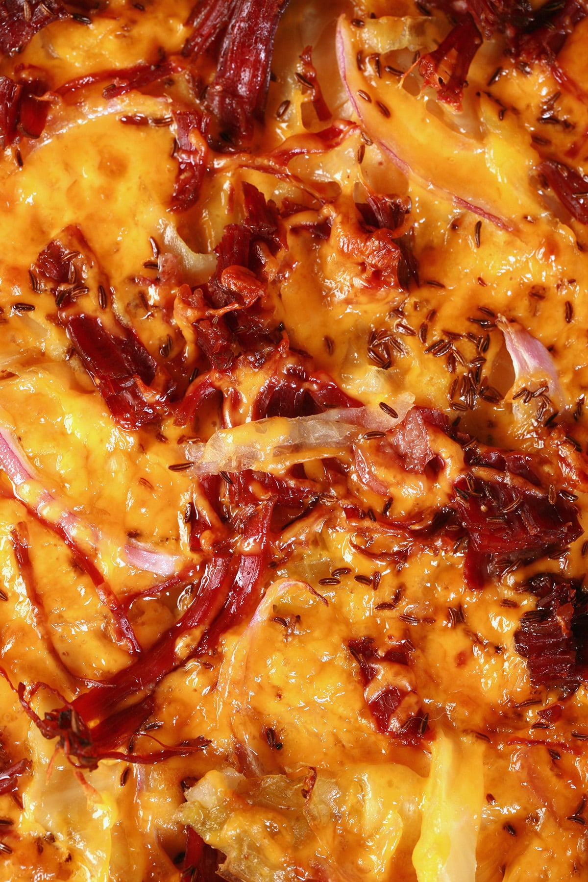 An overhead view of an Irish Pizza - a large rye crust pizza with cabbage, corned beef, cheddar, caraway seeds, and more.