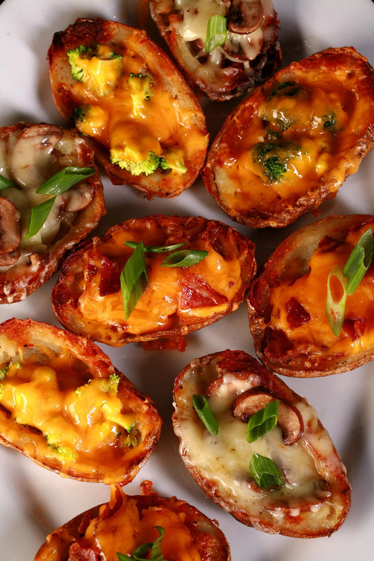 A plate of loaded bacon roasted potato skins, with various toppings.