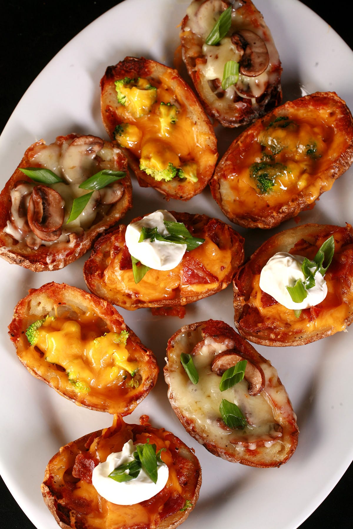 A plate of loaded potato skins, with various toppings.