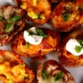 A plate of loaded potato skins, with various toppings.