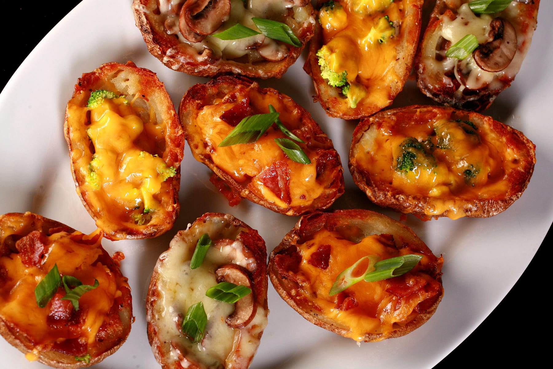 A plate of loaded bacon roasted potato skins, with various toppings.