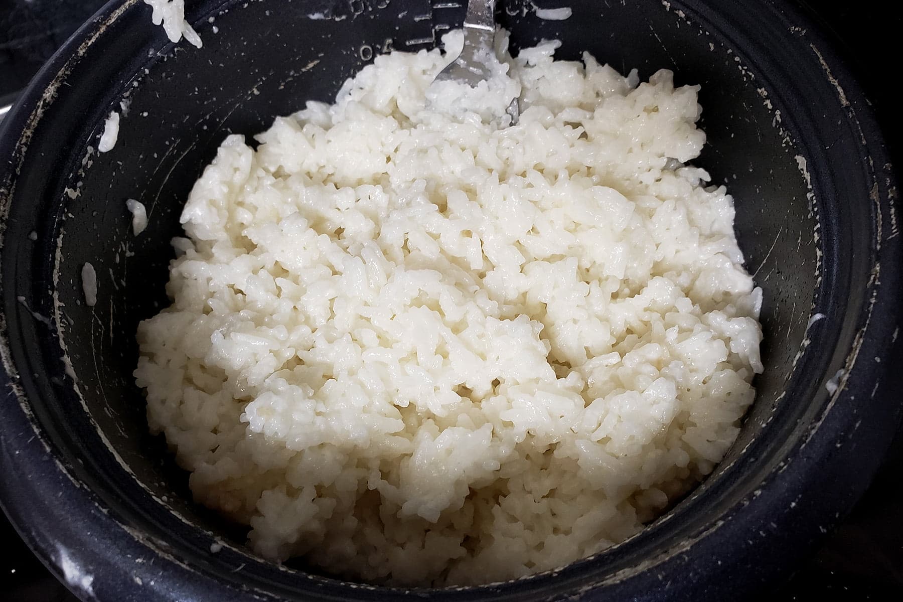 Fluffy white rice is shown inside a rice cooker.