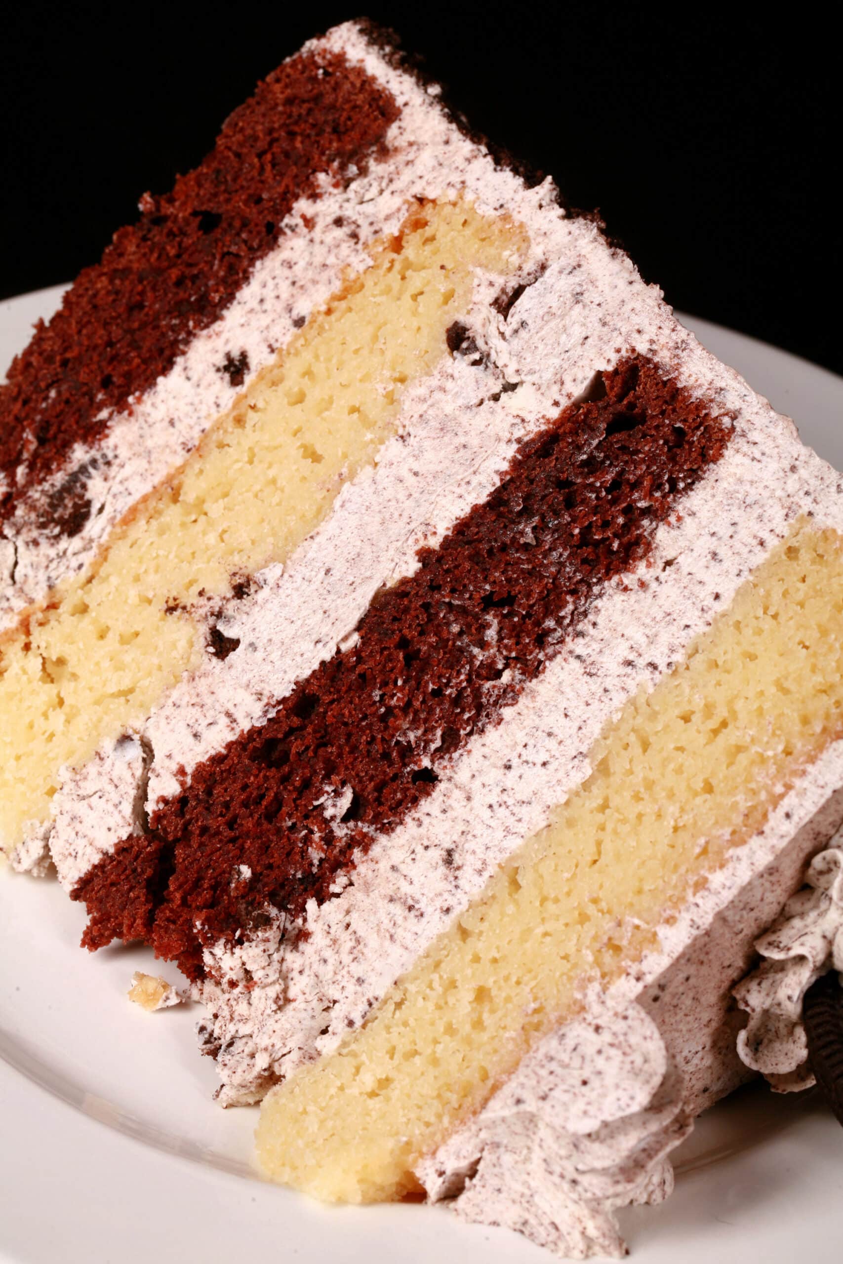 A slice of cookies and cream cake - chocolate and vanilla layers of cake separated with layers of cookies and cream icing.