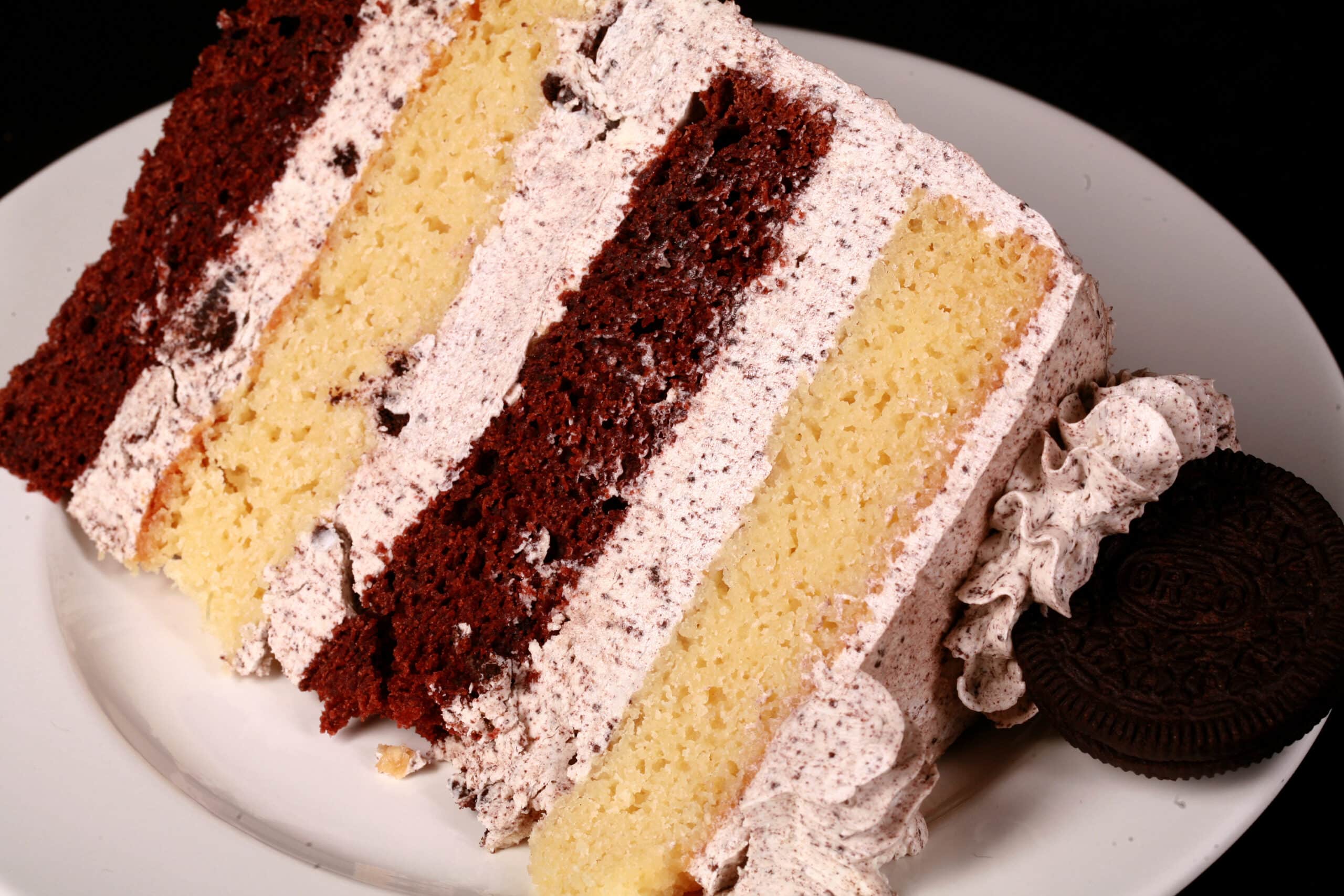 A slice of cookies and cream cake - chocolate and vanilla layers of cake separated with layers of cookies and cream icing.