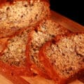 A sliced loaf of easy banana bread with walnuts, on a wooden cutting board.