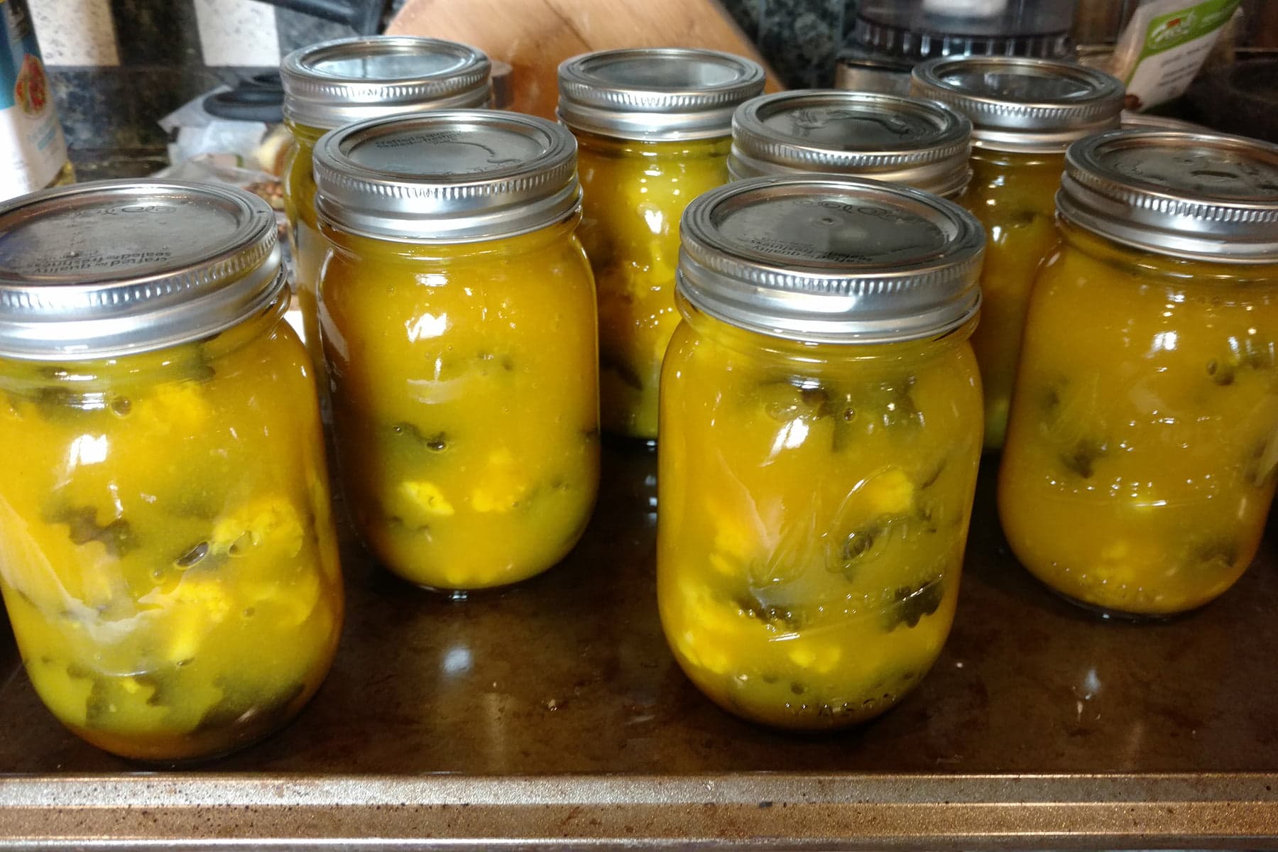 8 jars of yellow Sweet Mustard pickles, on a counter.