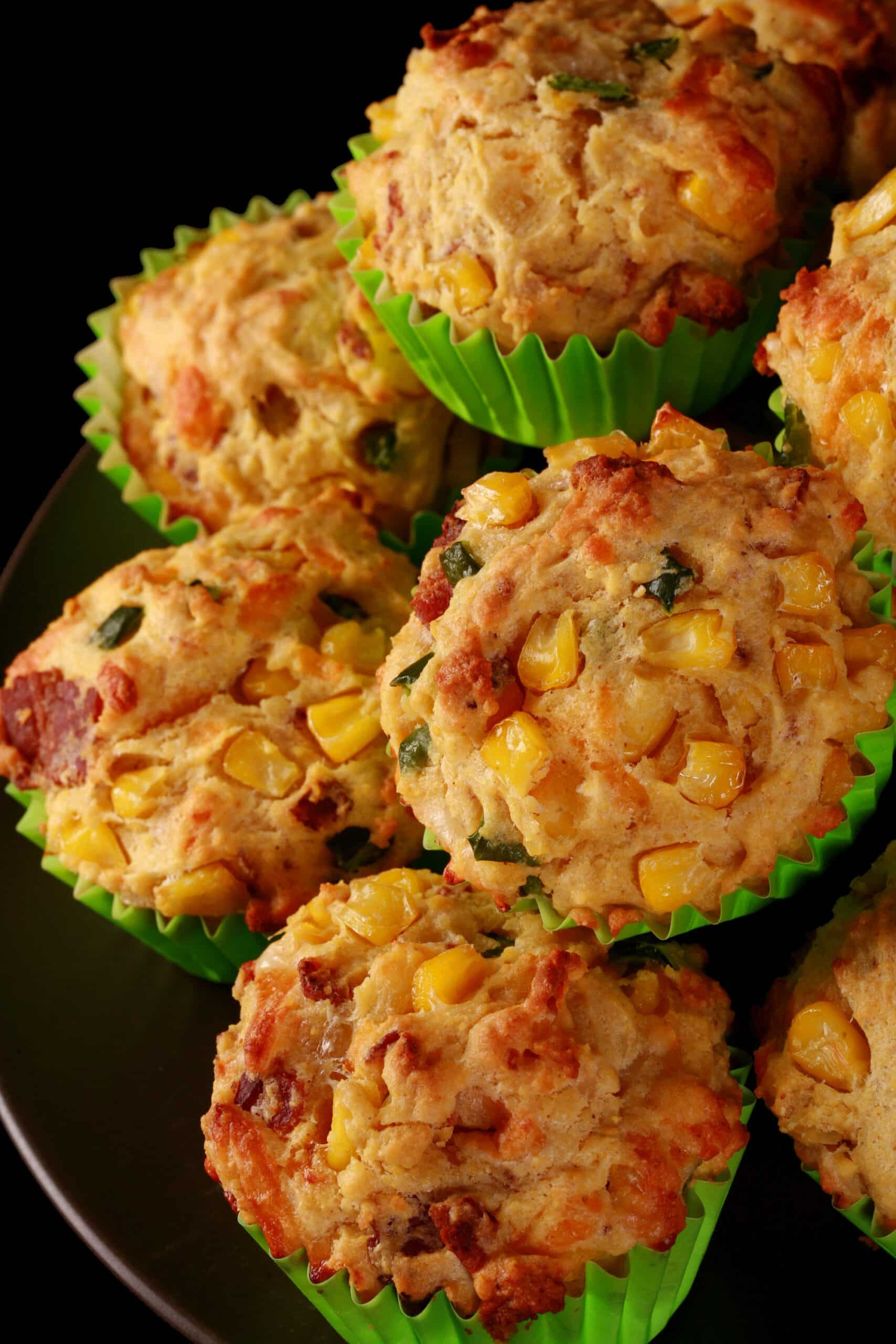 A plate of loaded breakfast corn muffins, with bacon, jalapeno, and corn kernels showing.