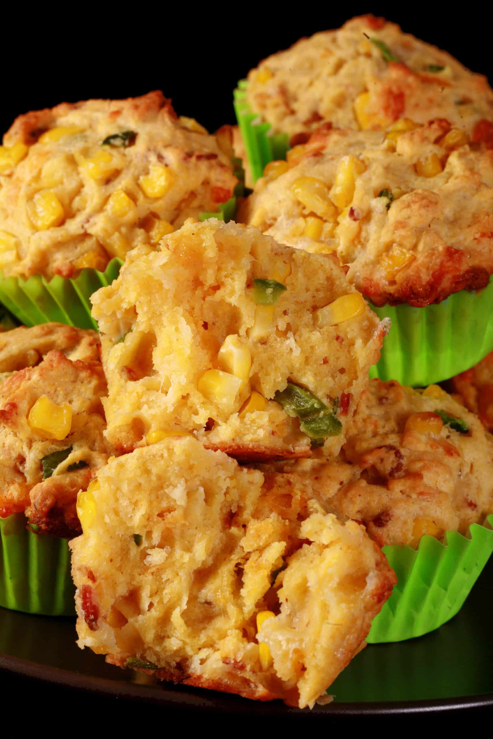 A plate of loaded breakfast corn muffins, with bacon, jalapeno, and corn kernels showing.