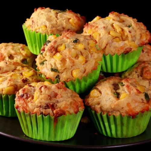 A plate of loaded breakfast corn muffins, with bacon, jalapeno, and corn kernels showing.