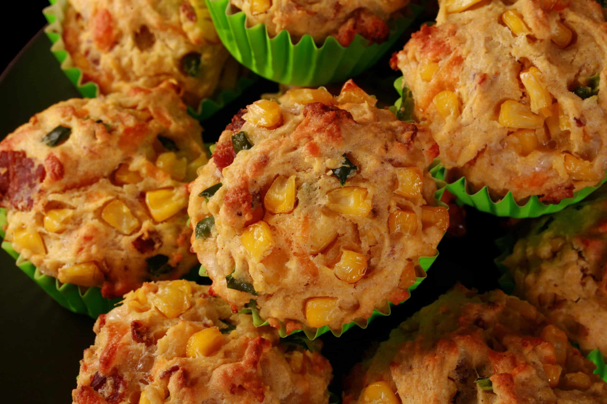 A plate of loaded breakfast corn muffins, with bacon, jalapeno, and corn kernels showing.