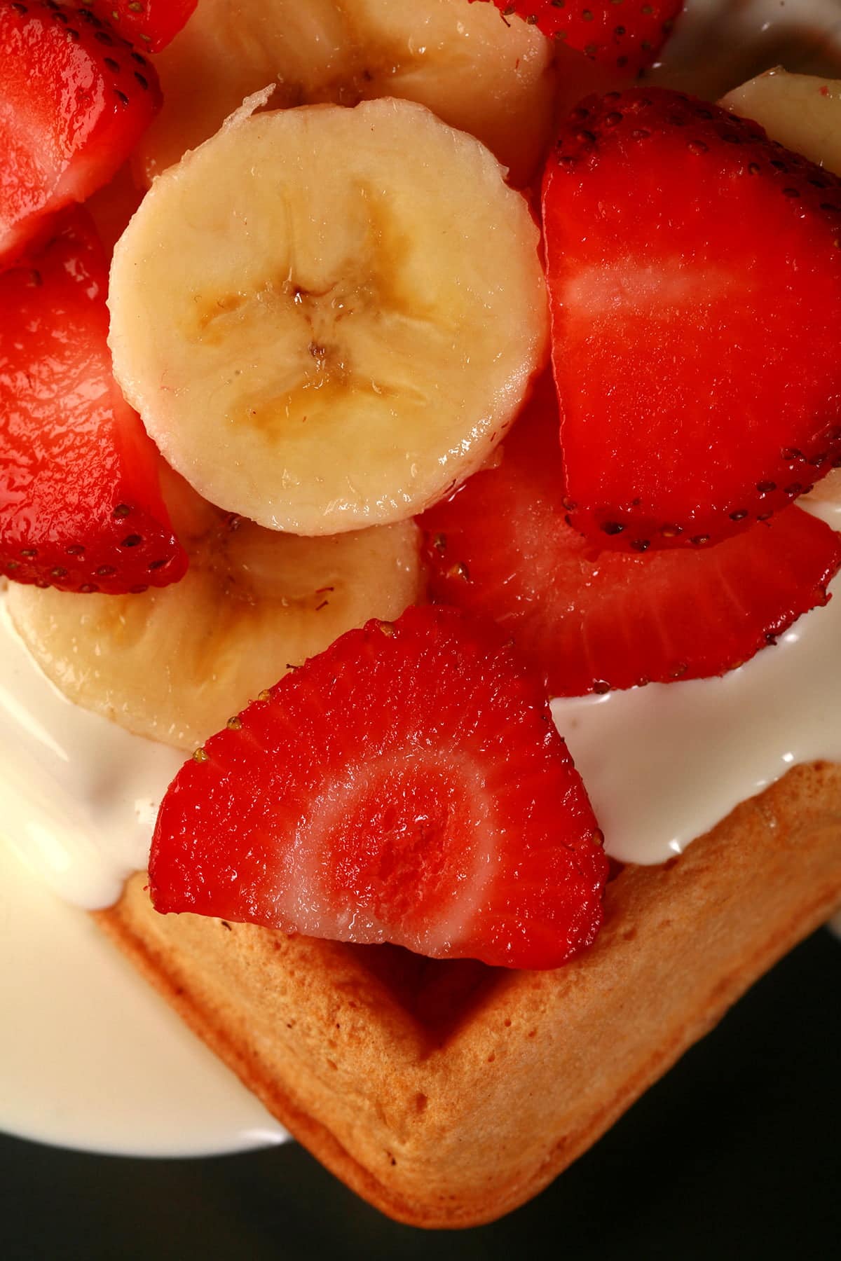 2 Ambrosia Belgian waffles - Belgian waffles with cream cheese sauce, topped with sliced strawberries and sliced bananas - on a blue plate.