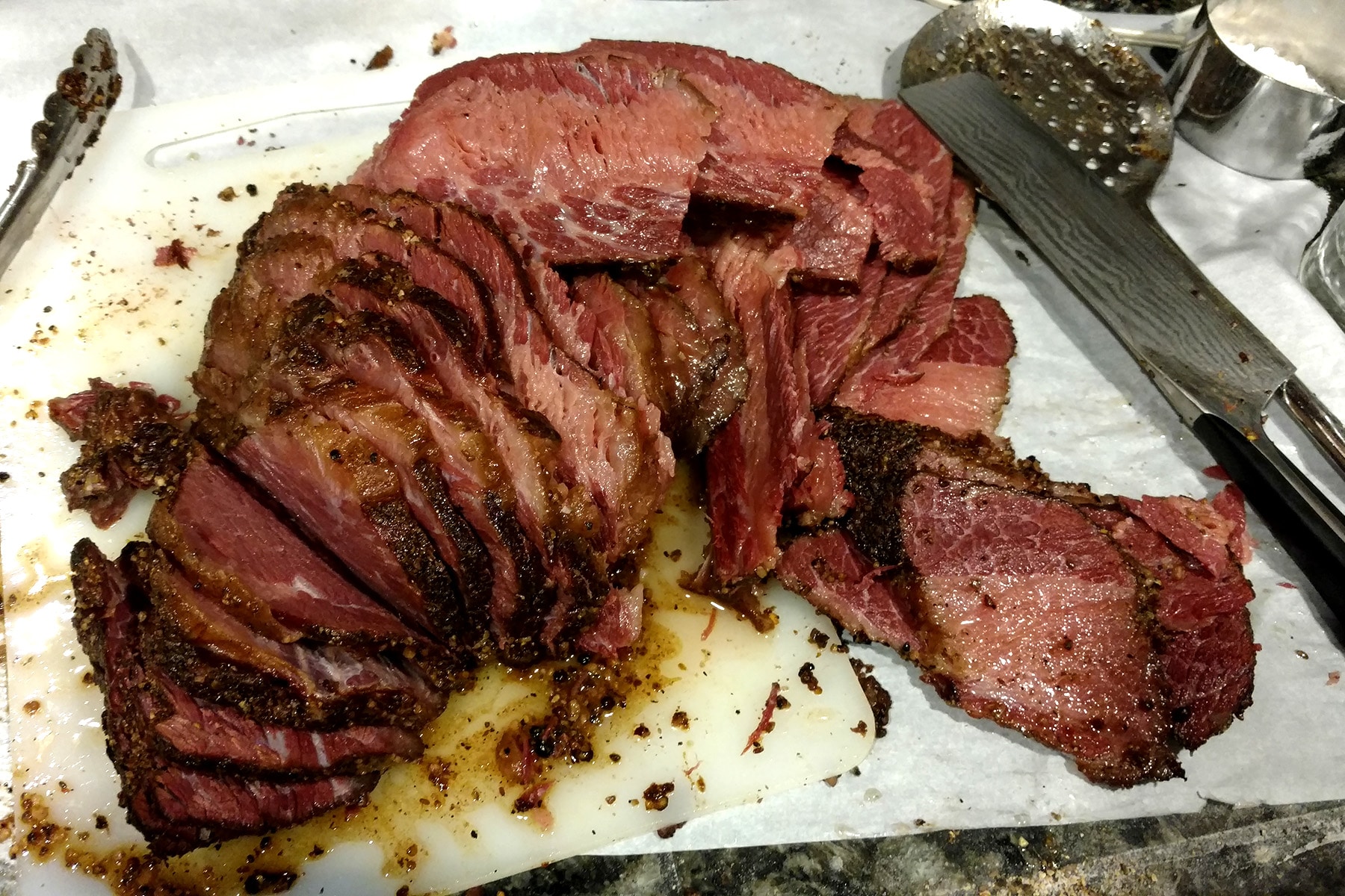 A large chunk of Montreal Smoked Meat, all sliced up on a cutting board.