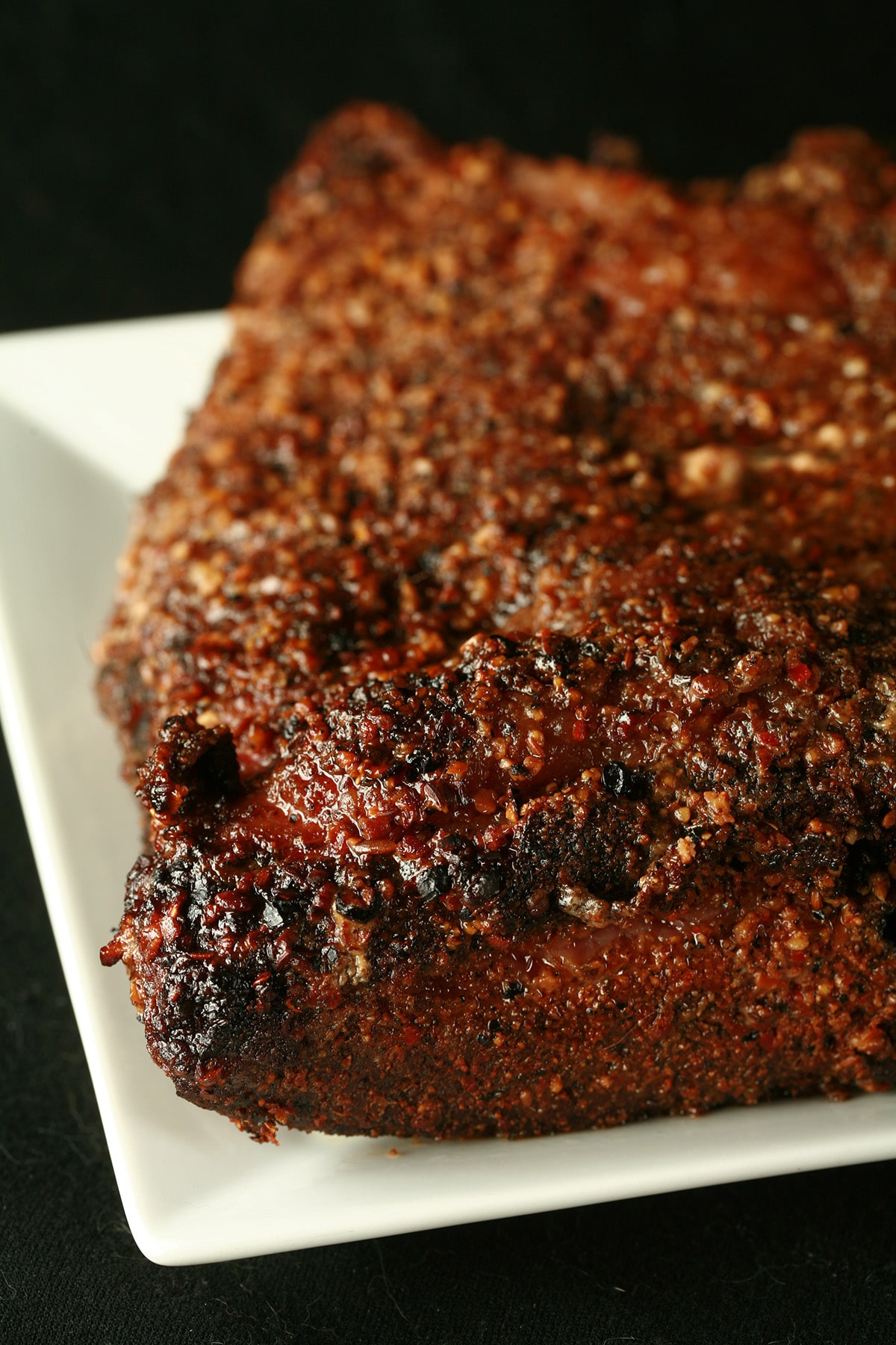 A large slab of unsliced Montreal Smoked Meat. The outside is crusted with montreal steak spice.