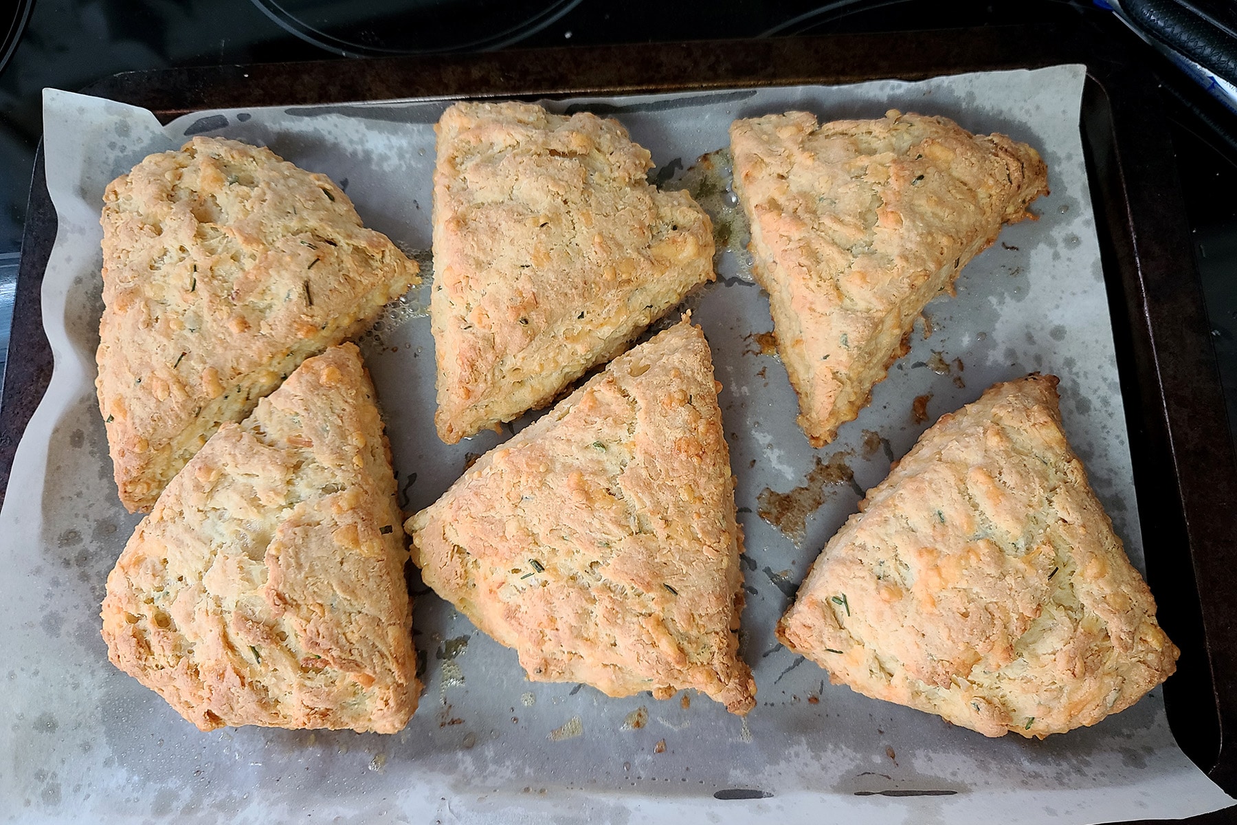 6 lightly golden savoury scones on a parchment lined baking sheet.