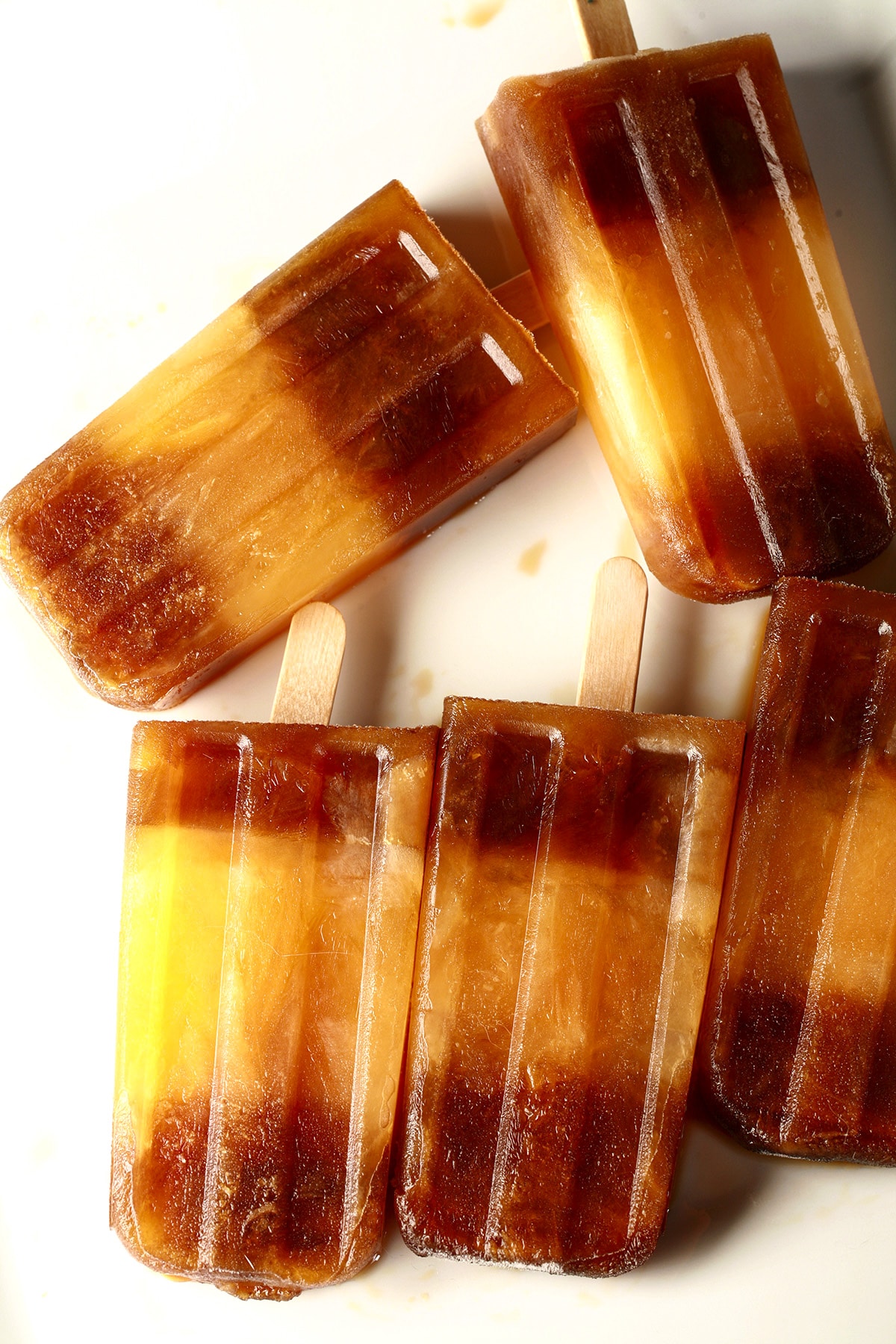 Several "Space Shuttle" popsicles - frozen root beer popsicles with a stripe of orange soda in the middle - are laid out on a white plate.