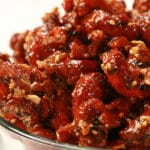 A close up view of Everything Honey Glazed Cashews in a glass bowl. They are crusted with a deep reddish brown caramel, and coated with bagel seasoning.