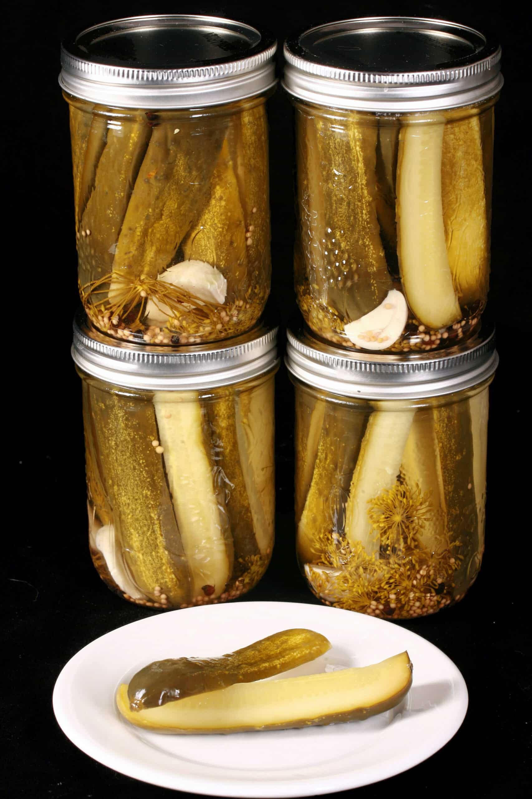 A pickle spears in front of several jars of homemade pickles.