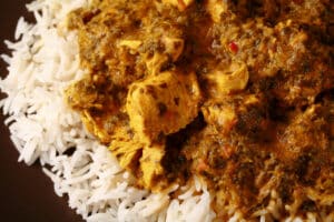 A plate of coriander chicken curry, served over basmati rice.