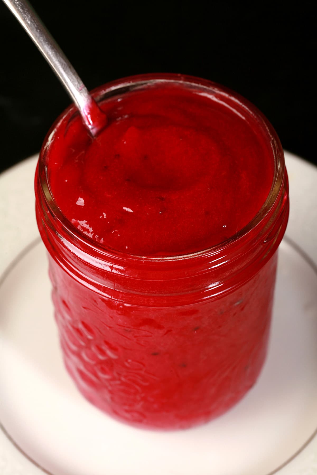 A close up photo of a jar of blackcurrant curd.