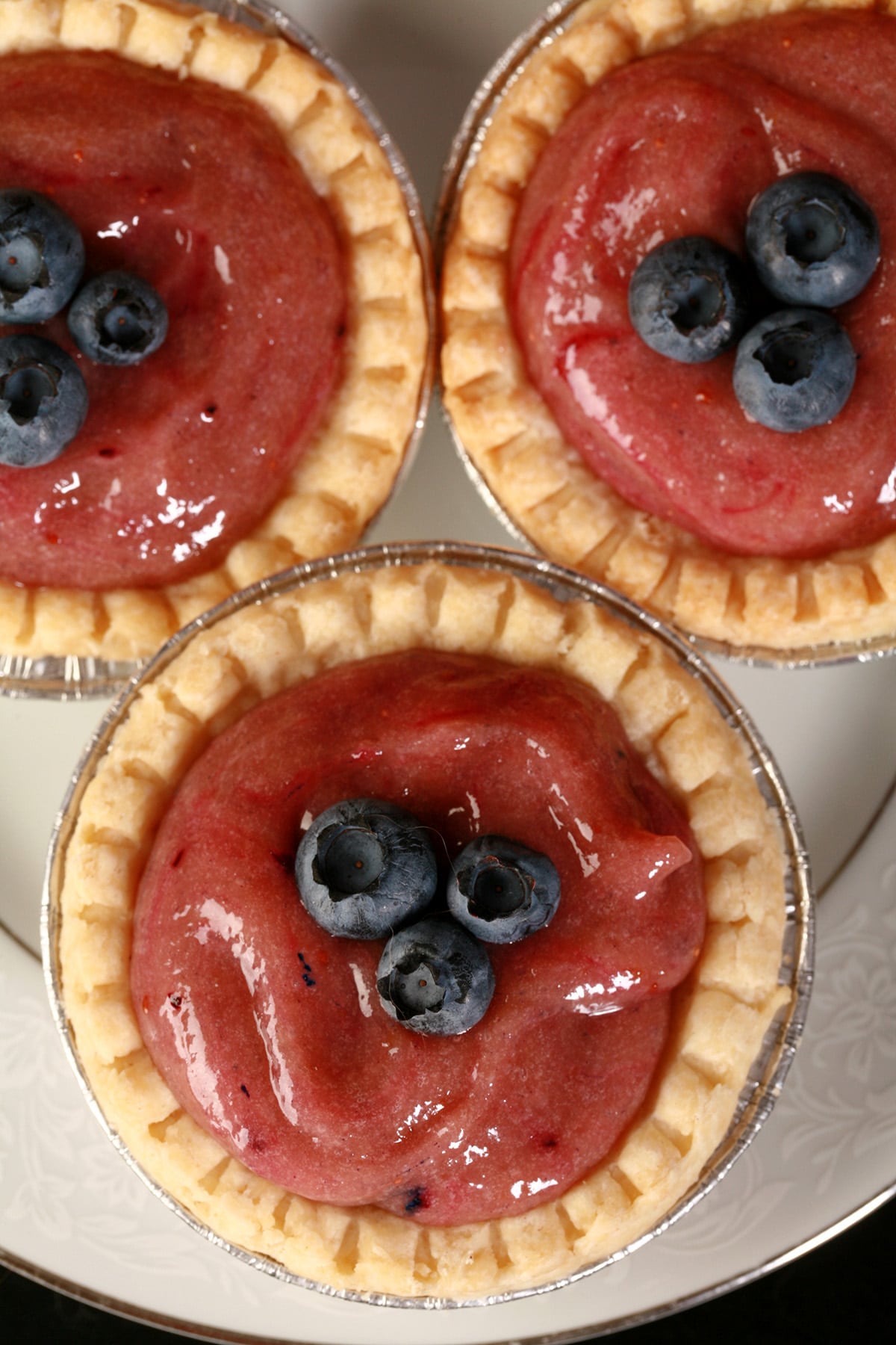 3 blueberry tarts on a plate.