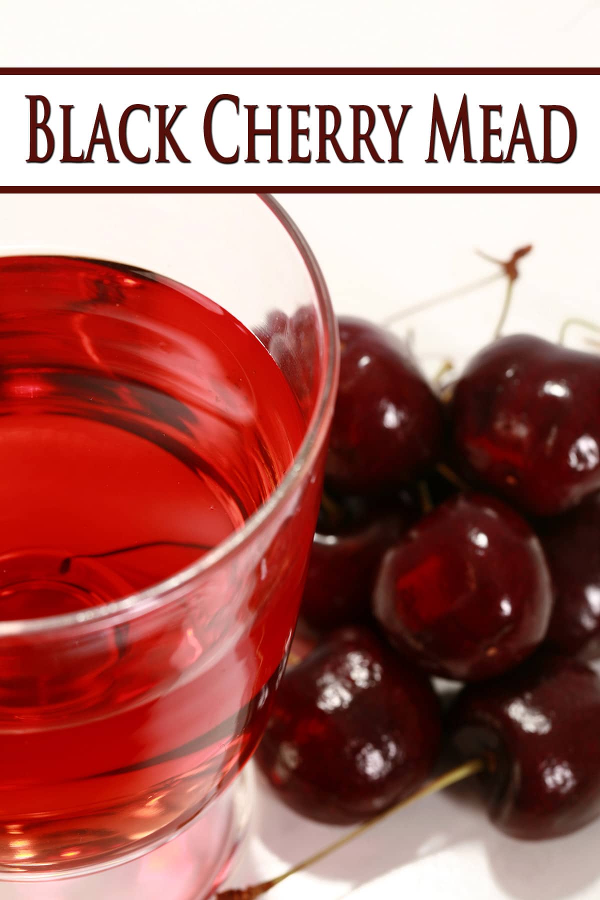A glass of black cherry mead, next to a pile of black cherries.