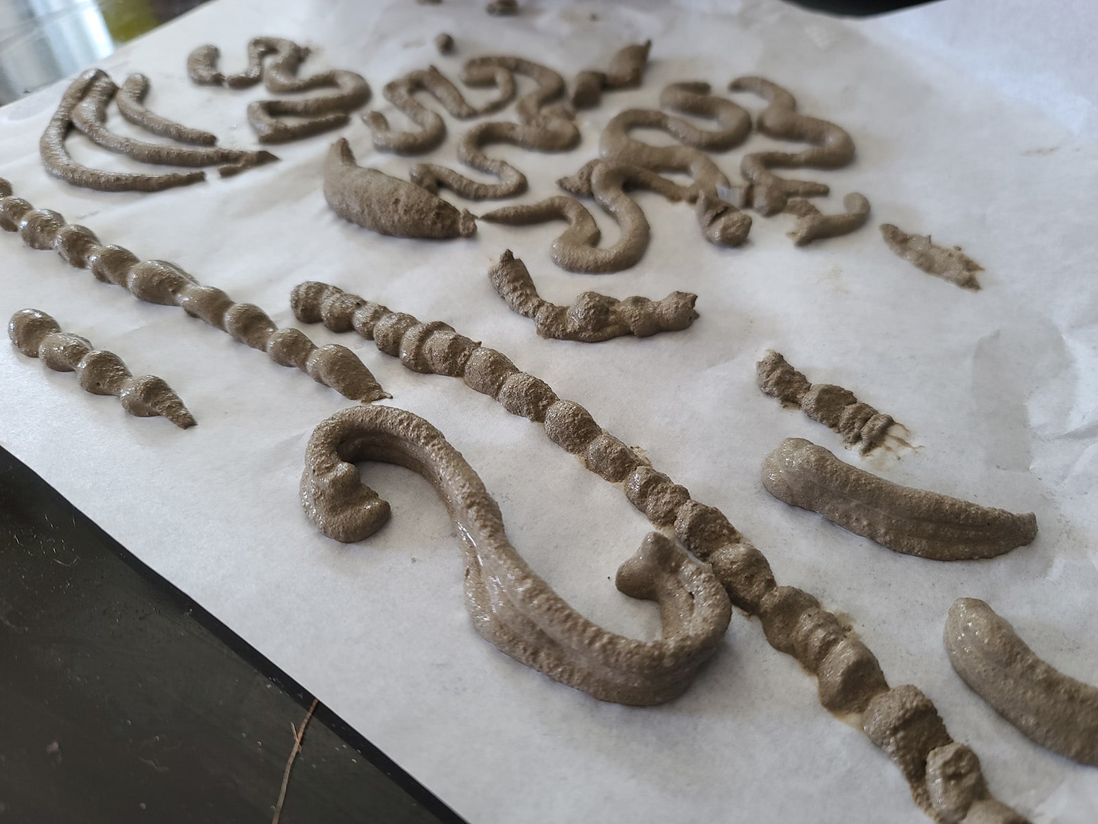 Cement swirls and scrolls piped onto parchment paper.