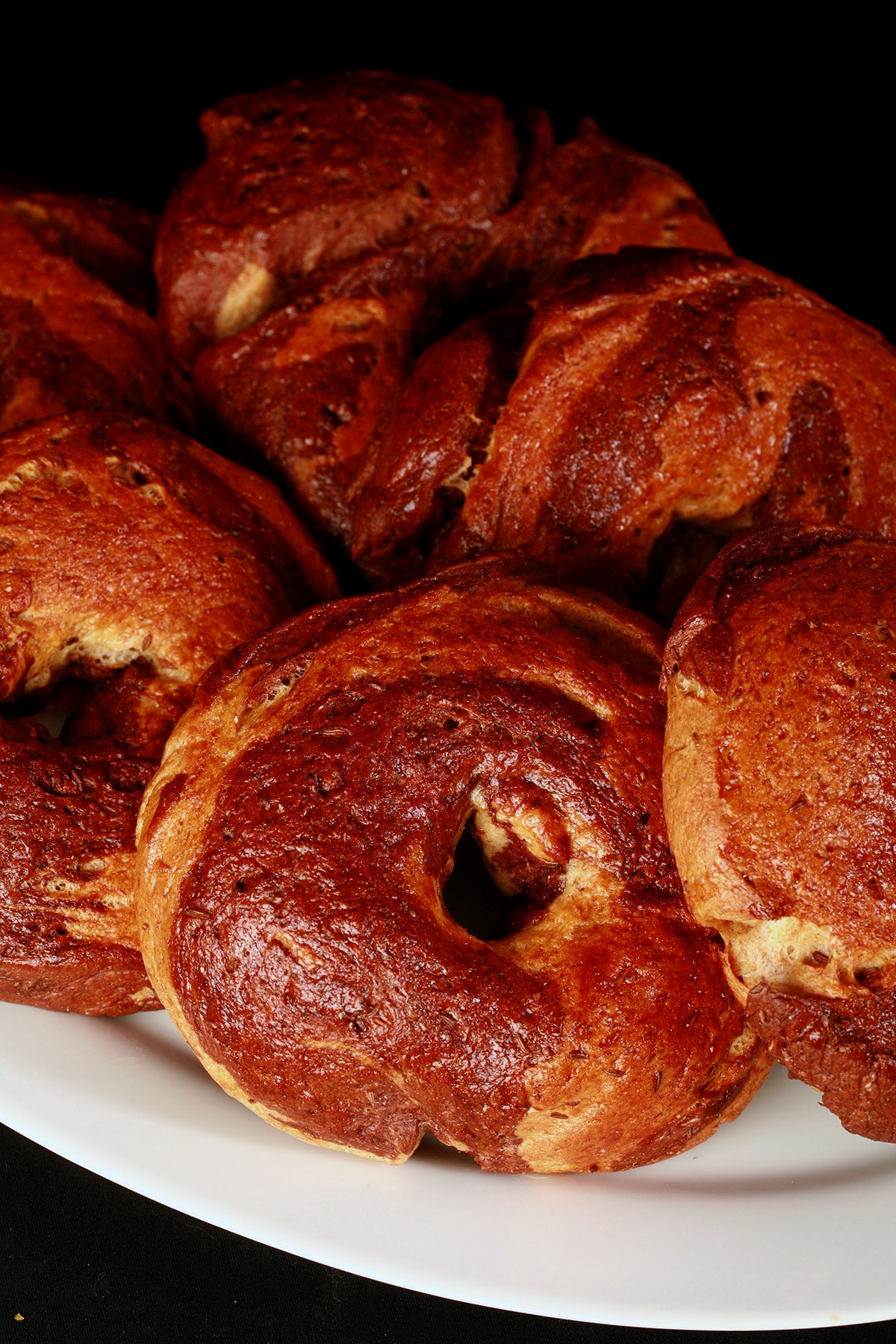 A plate of 6 golden brown marbled rye bagels.