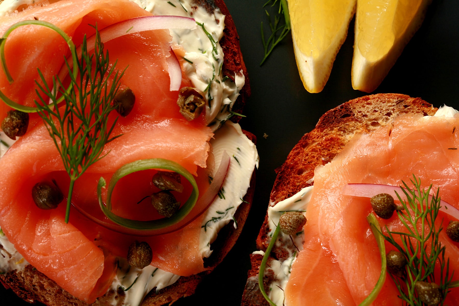 A toasted bagel open face sandwich with smoked salmon, cream cheese, capers, and onions.