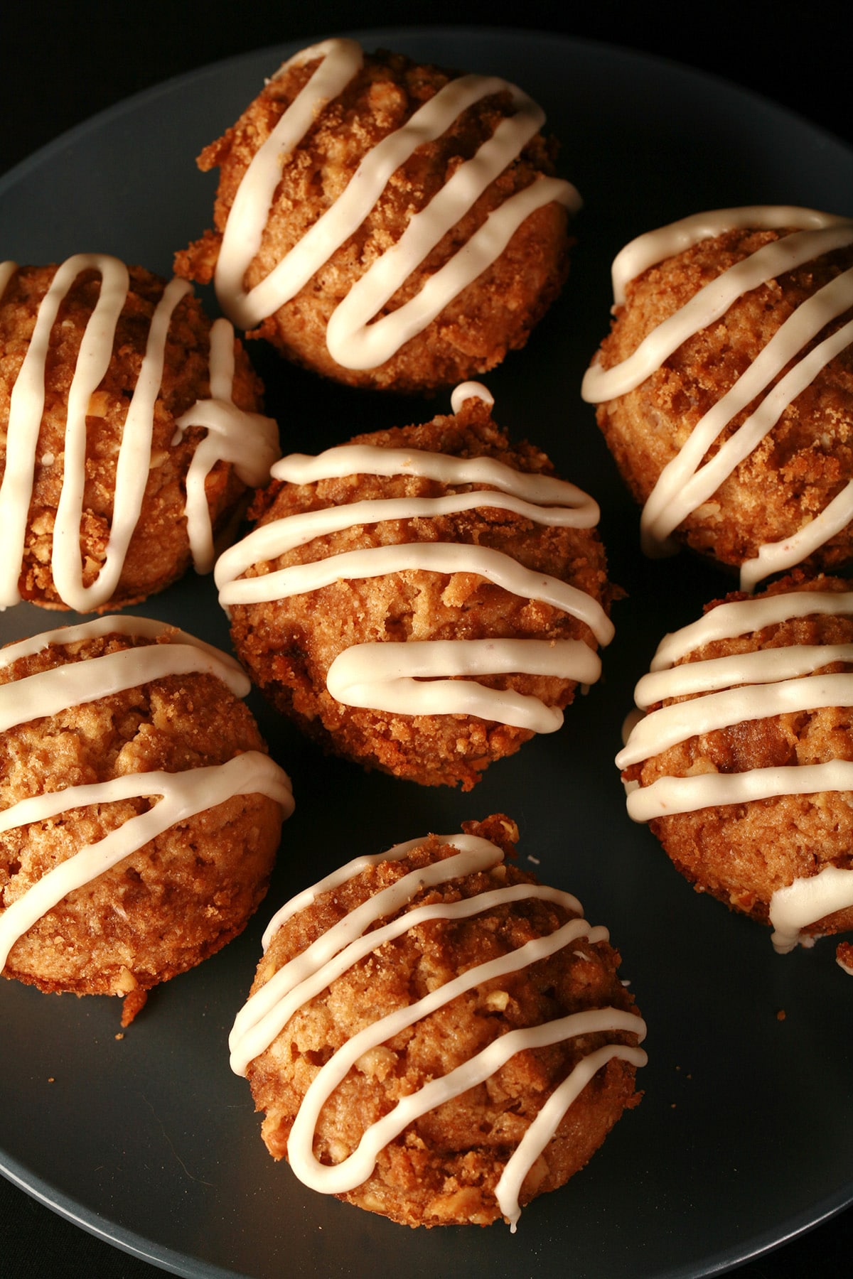 A plate of nutmeg coffee cake muffins, each drizzled with maple nutmeg glaze.