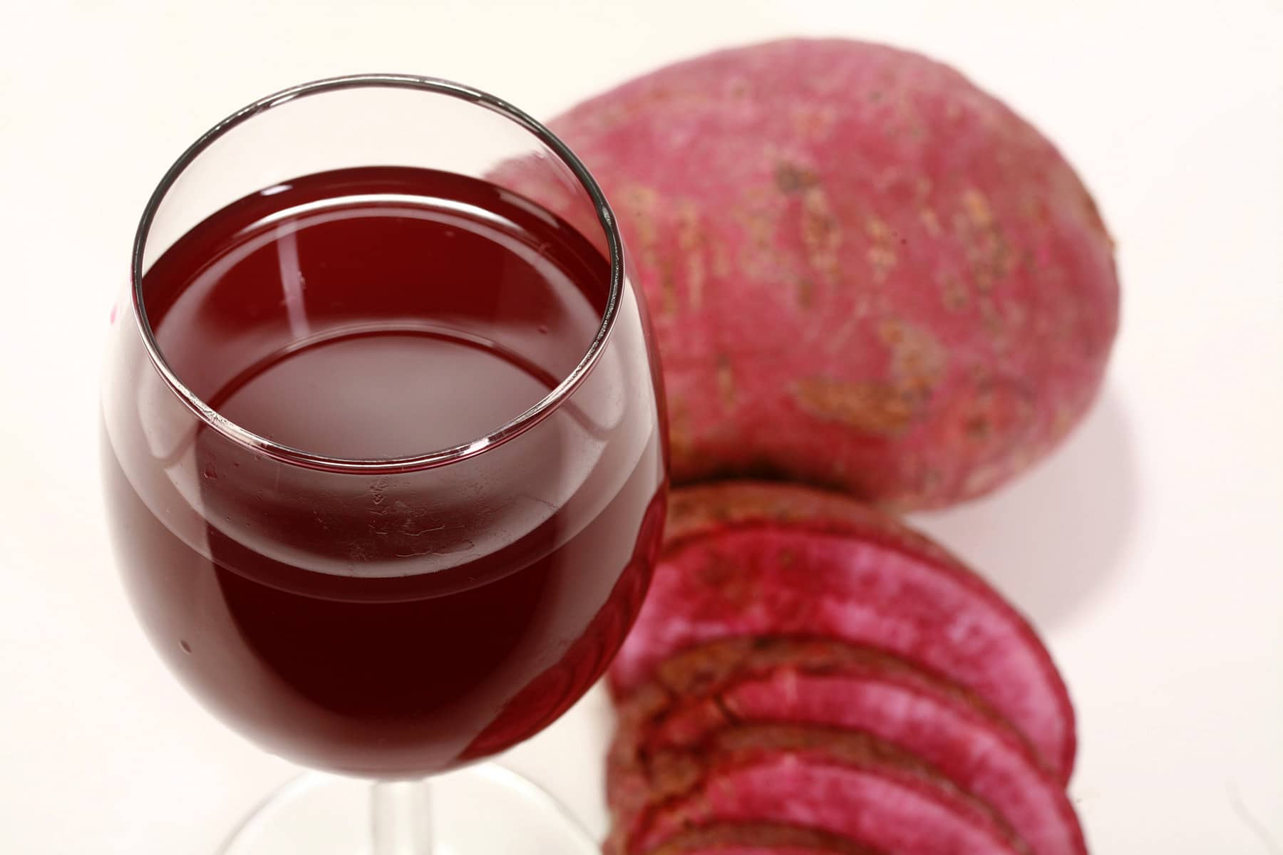 A wine glass with deep purple ube wine, next to a sliced up ube - purple sweet potato.