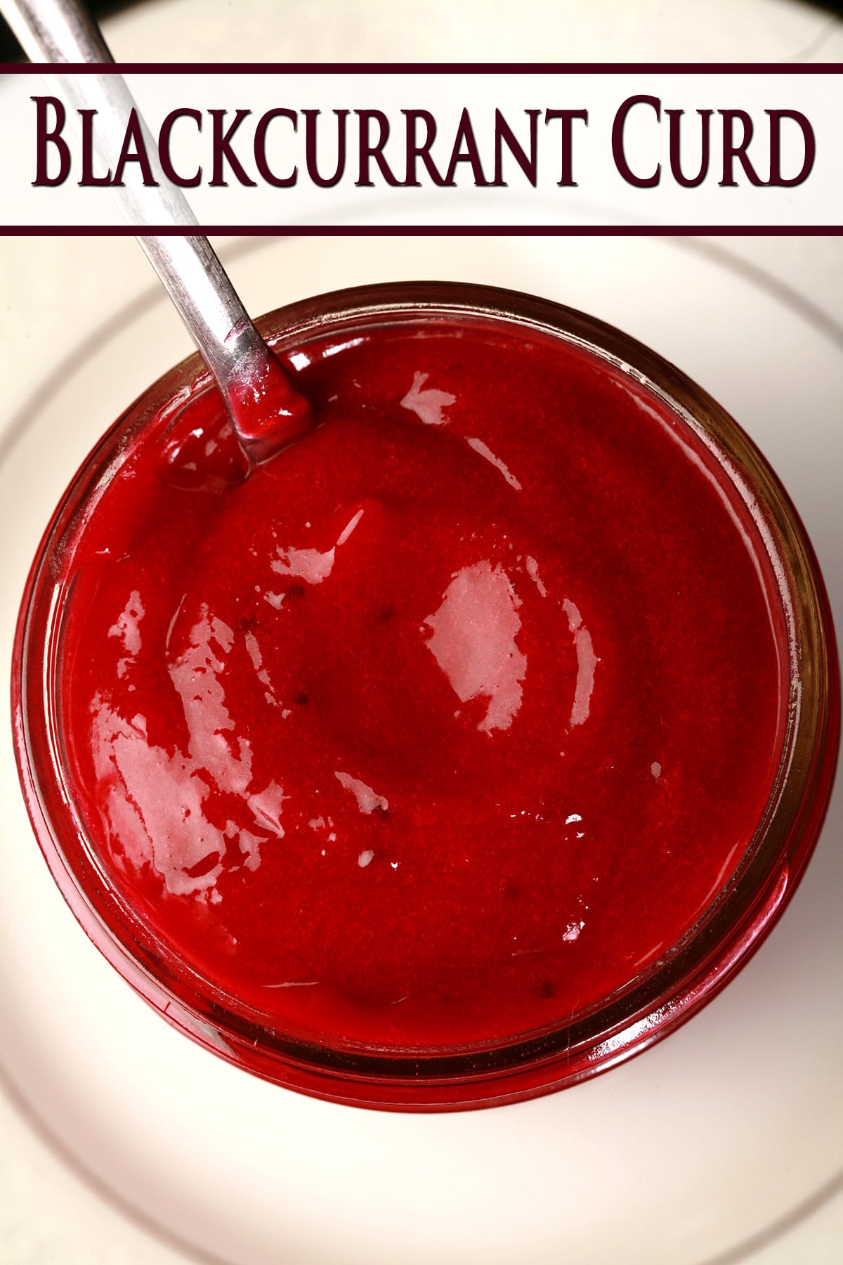 A close up photo of a jar of blackcurrant curd.