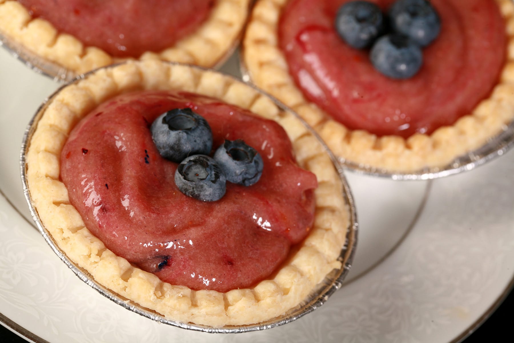 3 blueberry tarts on a plate.