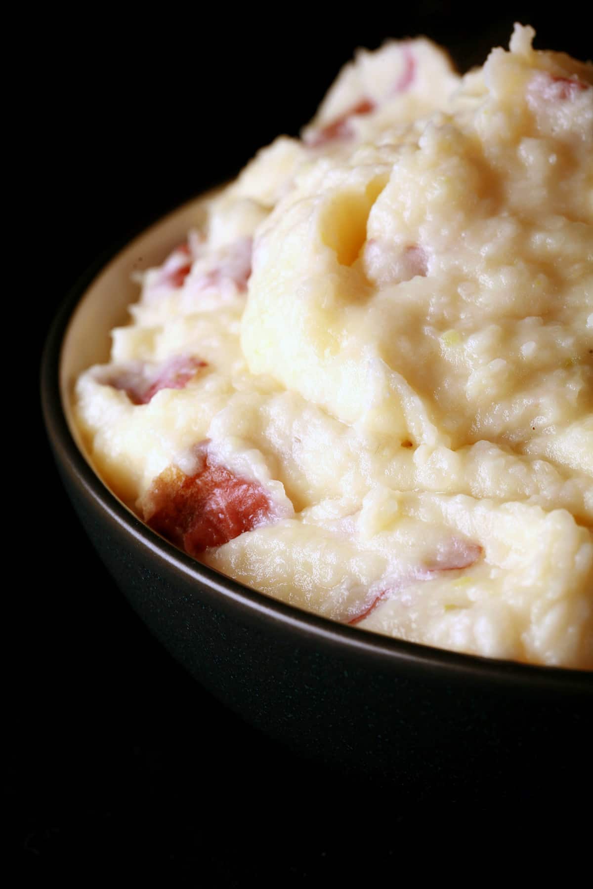 A close up photo of a bowl of gouda mashed potatoes.