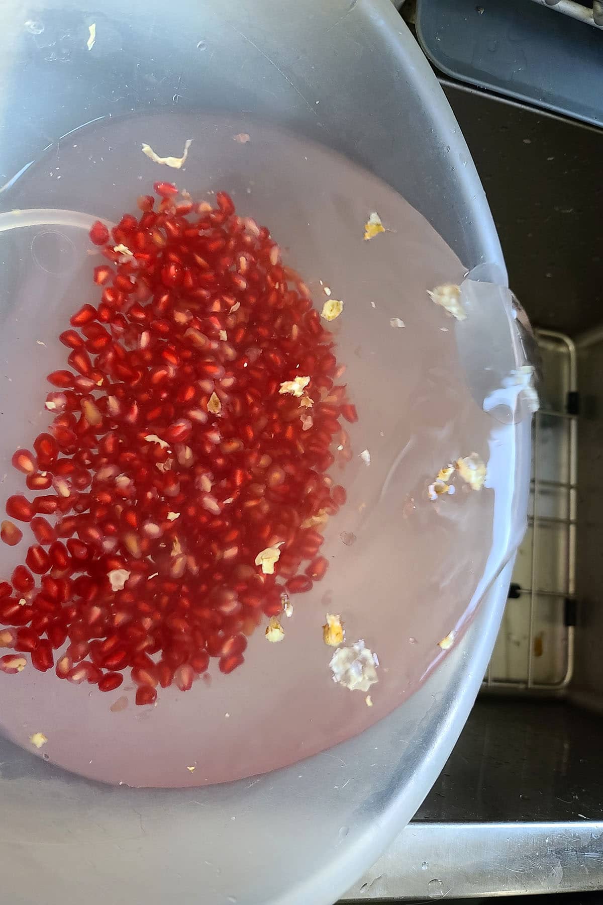 Water and bits of membrane being poured off the pomegranate arils.