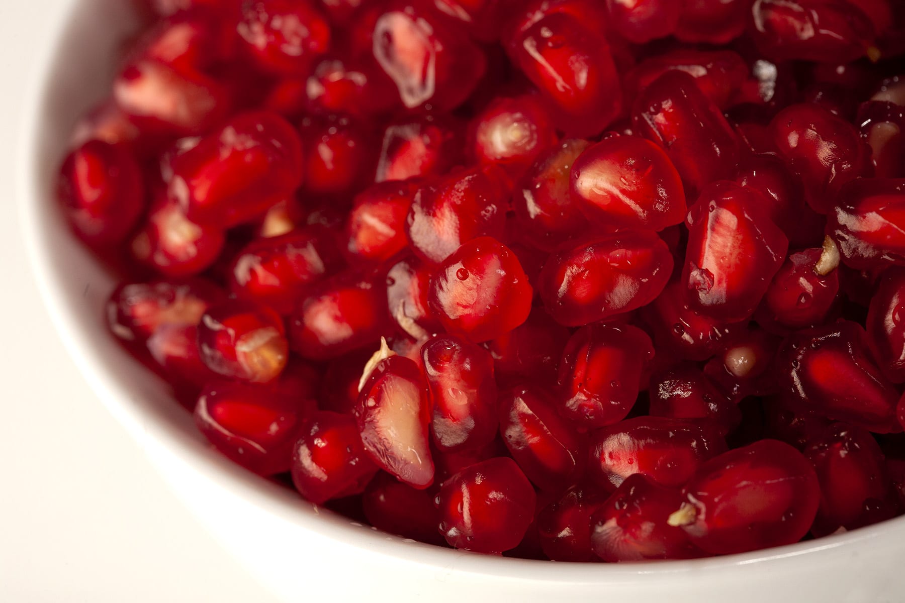 A close up view of a bowl of pomegranate seeds.