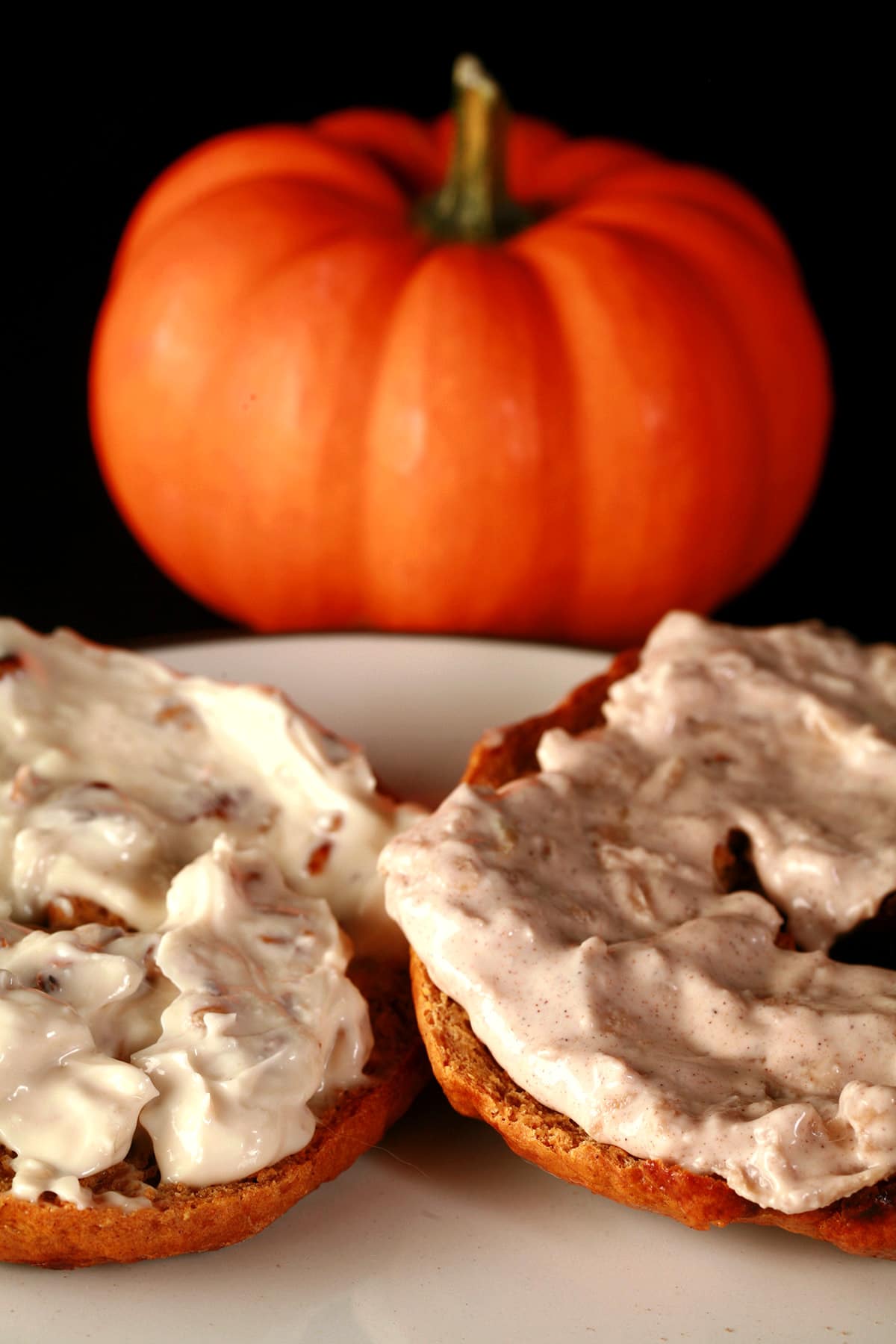 A split and toasted maple pumpkin spice bagel spread with cream cheese.