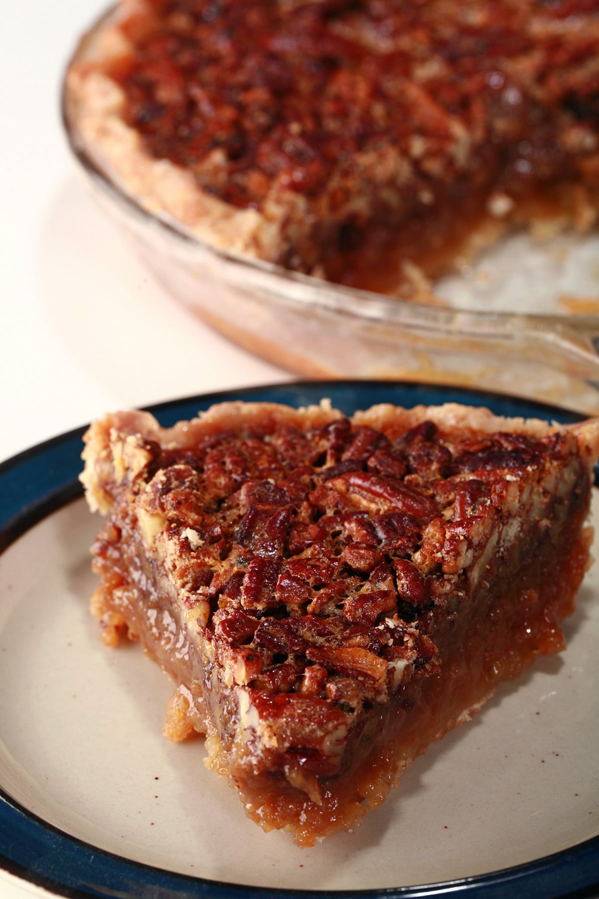 A slice of Southern Comfort pecan pie, in front of the whole pie.