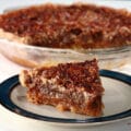 A slice of Southern Comfort pecan pie, in front of the whole pie.